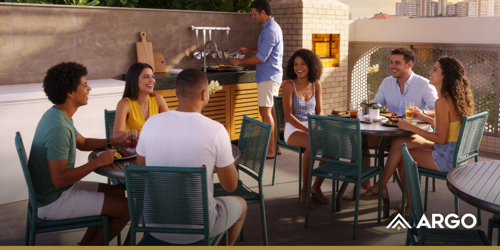 Família e amigos em área gourmet com churrasqueira em um terraço, ao pôr do sol